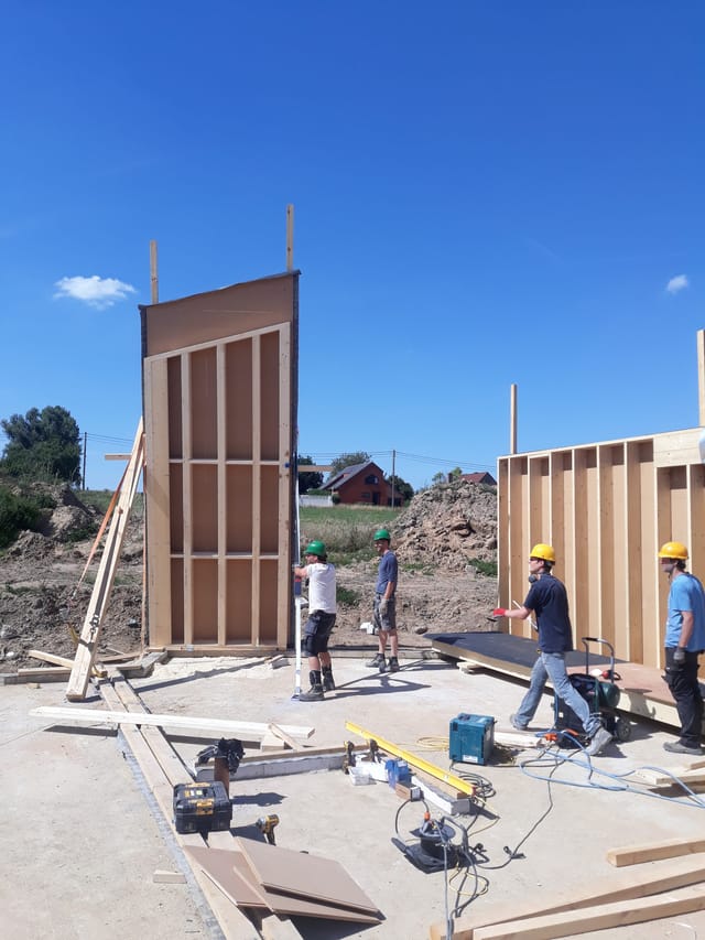 Panneaux de mur en ossature bois dressés sur le chantier-école, ciel bleu