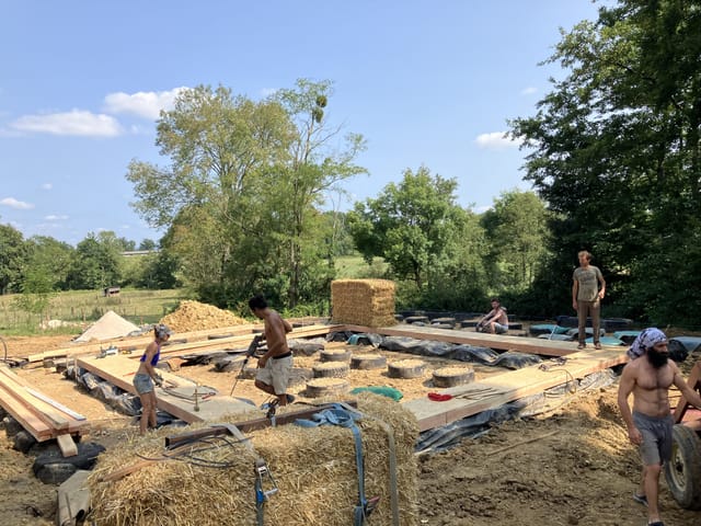 Chantier participatif de paille porteuse en plein champ, murs en gros ballots