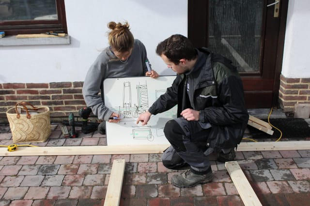 Deux personnes agenouillées étudient un plan de chantier